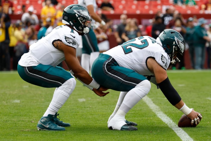 Jalen hurts kneels down to receive a snap from Jason kelce